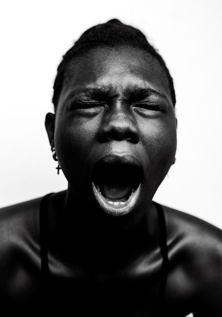 Black and white portrait of a person yawning with eyes closed, conveying emotion.