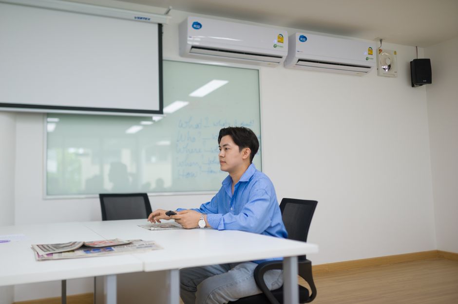 Businessman sits alone in modern office meeting room using technology.