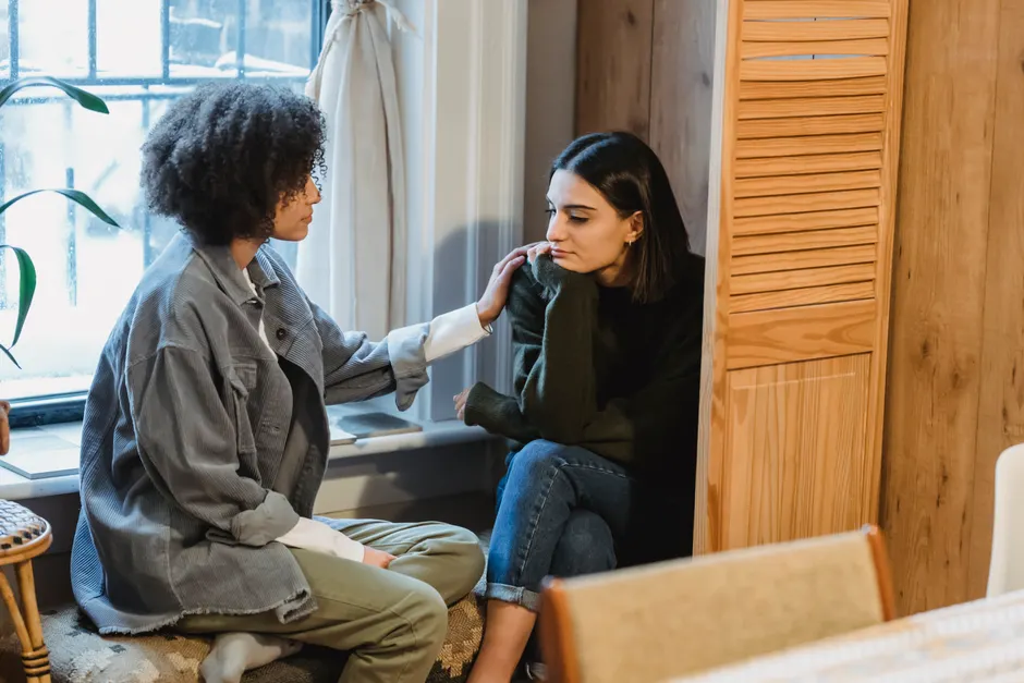 Trouble bipolaire : pourquoi le soutien social compte dans le suivi Calm young multiracial female best friends in casual clothes sitting near window and home and discussing discussing problems