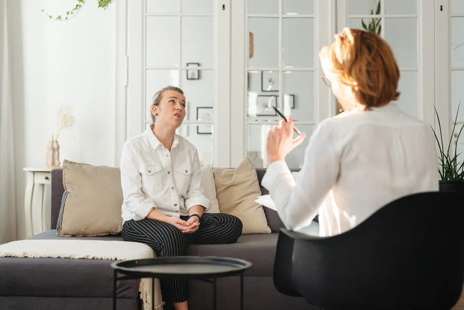 Casual conversation between two women seated in a stylish living room setting.