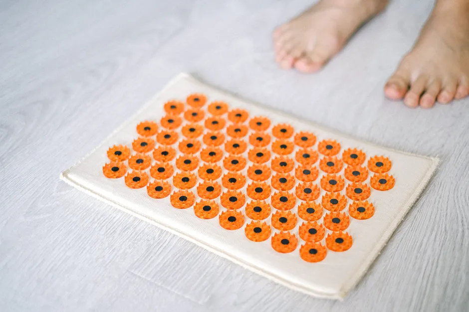 Close-up of a foot acupressure mat on a wooden floor, ideal for relaxation therapies.