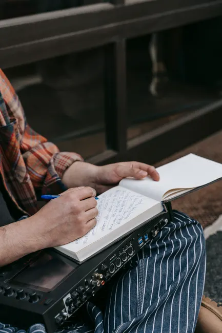 Close-up of a person writing in a notebook, capturing creativity and focus.