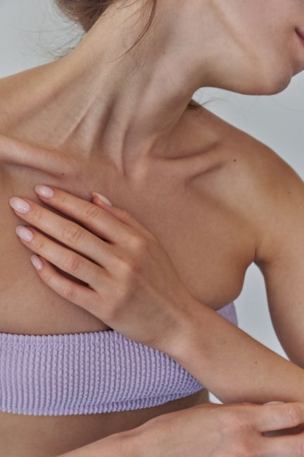 Close-up of a woman's hand resting on her collarbone, showcasing natural beauty.