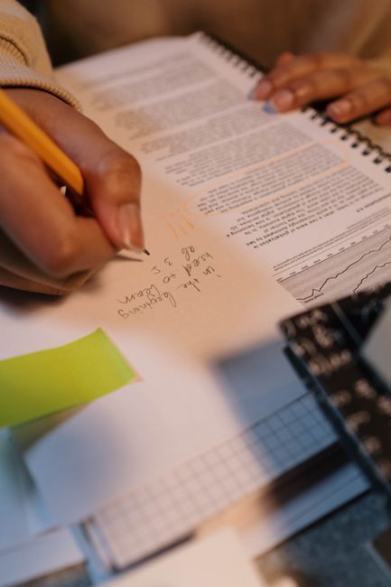Close-up of hand writing notes in a spiral notebook, emphasizing study and learning.