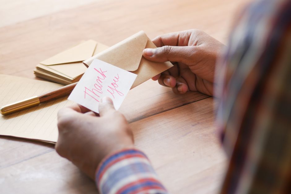 Sociopathe : 7 schémas à observer sans diagnostiquer Close-up of hands holding a thank you note in an envelope on a table.