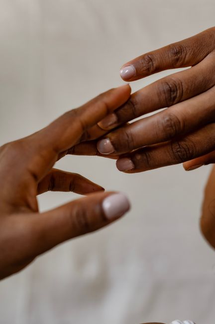Close-up of two hands with manicured nails gently touching, symbolizing connection and care.