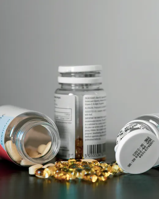 Close-up of various pill bottles and vitamins spilled on a table.