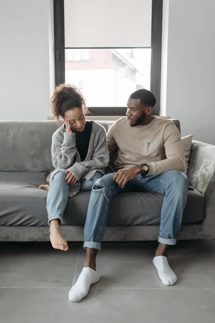 Concerned couple sitting indoors, addressing health issues and comfort together.