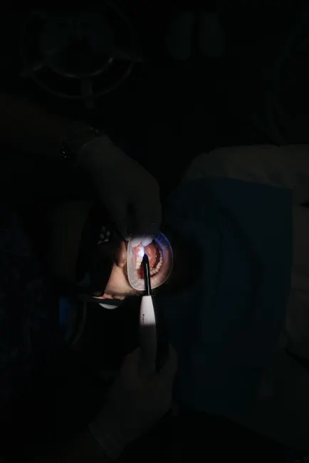 Dentist performing a dental procedure using medical instruments on a patient in a clinic.