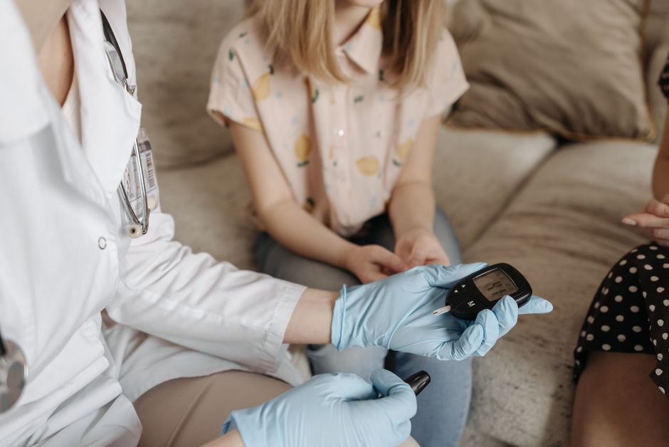 Doctor using a glucose meter to check a patient's blood sugar during a medical consultation.