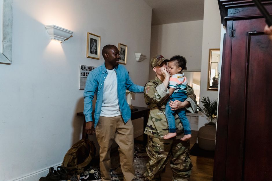 Emotional family reunion with a military mother, father, and child celebrating homecoming indoors.