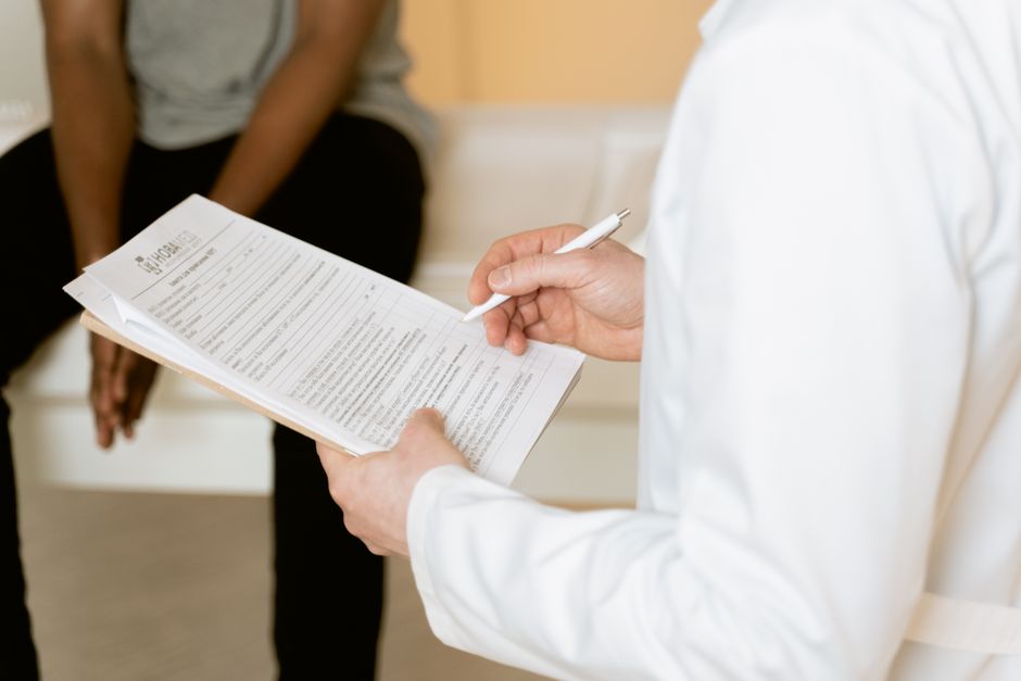 Test génétique en psychiatrie : ce qu’il peut dire, et ce qu’il ne peut pas Healthcare professional reviews medical form during patient consultation in a clinic setting.
