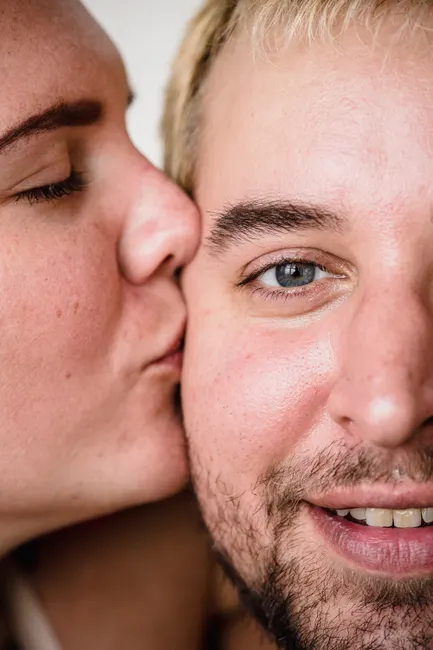 Intimate close-up of a couple sharing a tender moment with a loving kiss on the cheek.