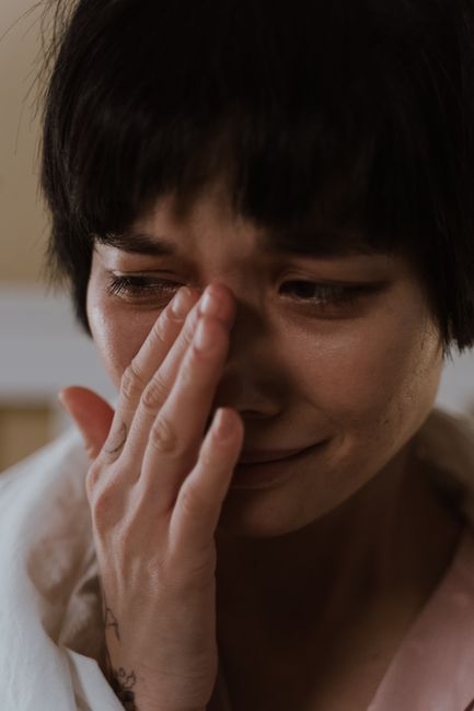 Intimate portrait of an Asian woman crying, expressing deep emotion and vulnerability.