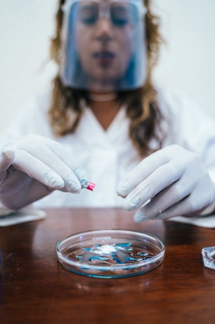 Laboratory scientist in protective gear conducting an experiment with petri dish.