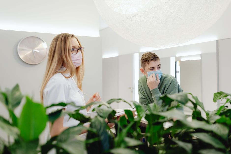 Man and woman wearing face masks in a clinic, discussing at a counter indoors.