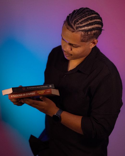 Man holding psychology books against a colorful backdrop with a thoughtful expression, perfect for educational and literature themes.