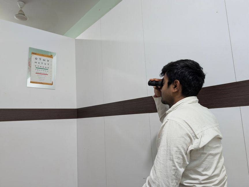 Man using binoculars to view an eye chart indoors. Vision test concept.