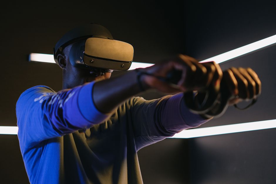 Man using VR headset and controllers in a futuristic room, engaged in gaming.