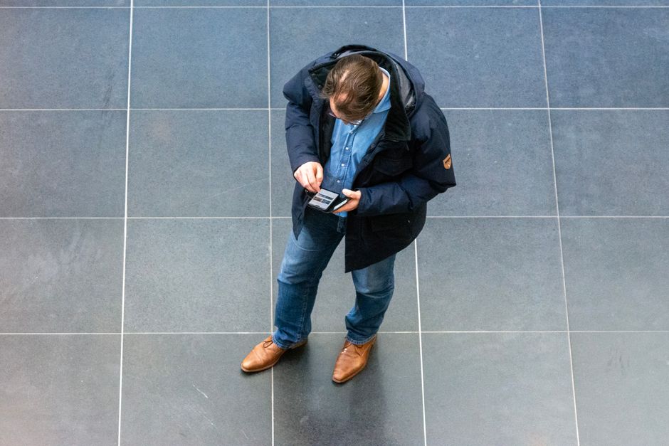 Limérence : quand l’attente amoureuse devient une boucle obsessionnelle Overhead view of a casually dressed man looking at his phone indoors.