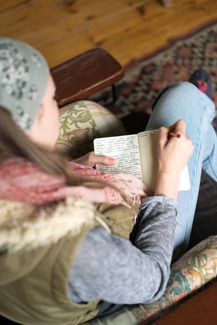 Person sitting indoors writing in a notebook, captured from above.