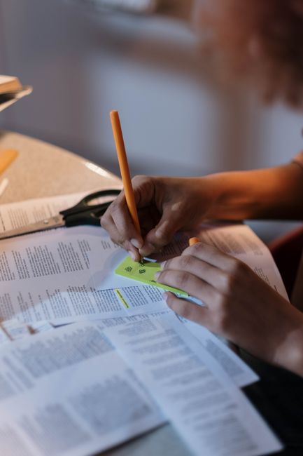 Person taking notes on papers with a yellow pen, enhancing study focus.