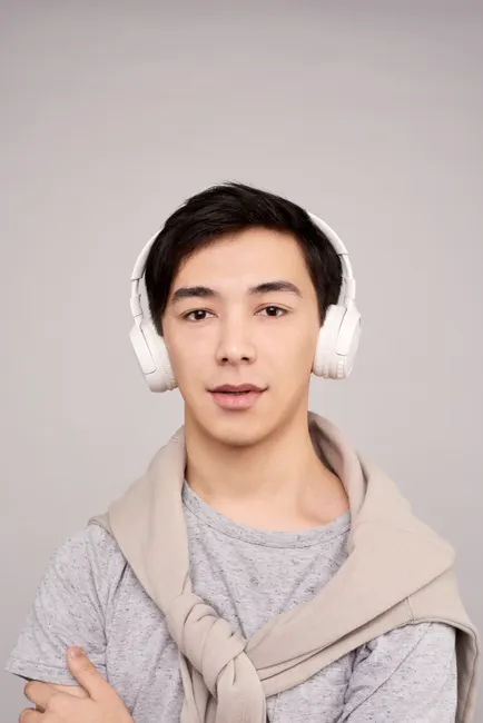 Portrait of a stylish young adult with headphones, wearing a casual grey outfit.
