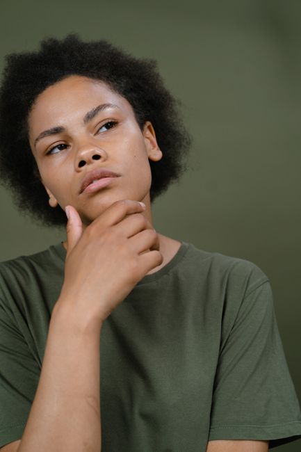 Portrait of a thoughtful person with afro hair in a studio setting.