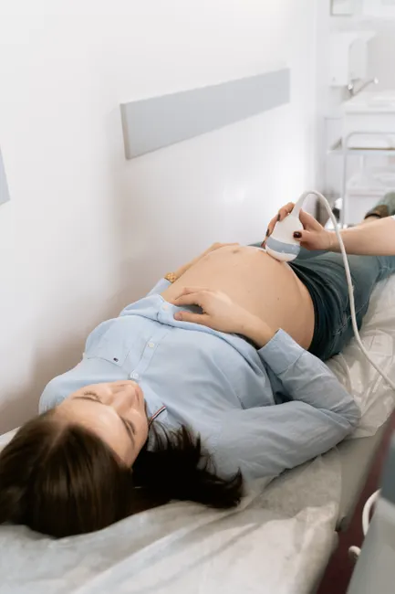 Pregnant woman receiving ultrasound in medical clinic for prenatal care.
