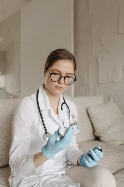 Professional female doctor in glasses and gloves examines medication indoors.