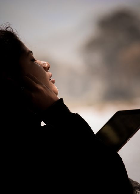 Side profile of a woman listening to music with headphones, experiencing relaxation outdoors.