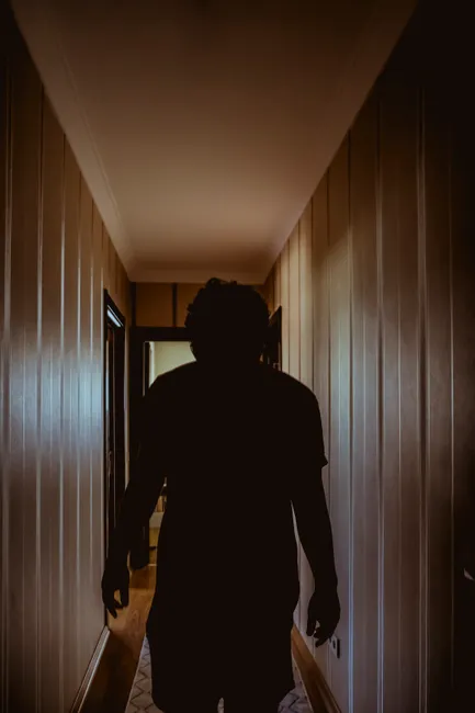 Silhouette of a person walking through a dimly lit hallway, creating a mysterious atmosphere.