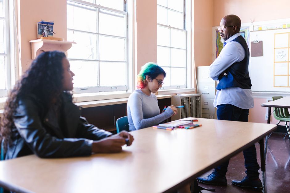 Teacher and students engaged in a classroom discussion with natural light.