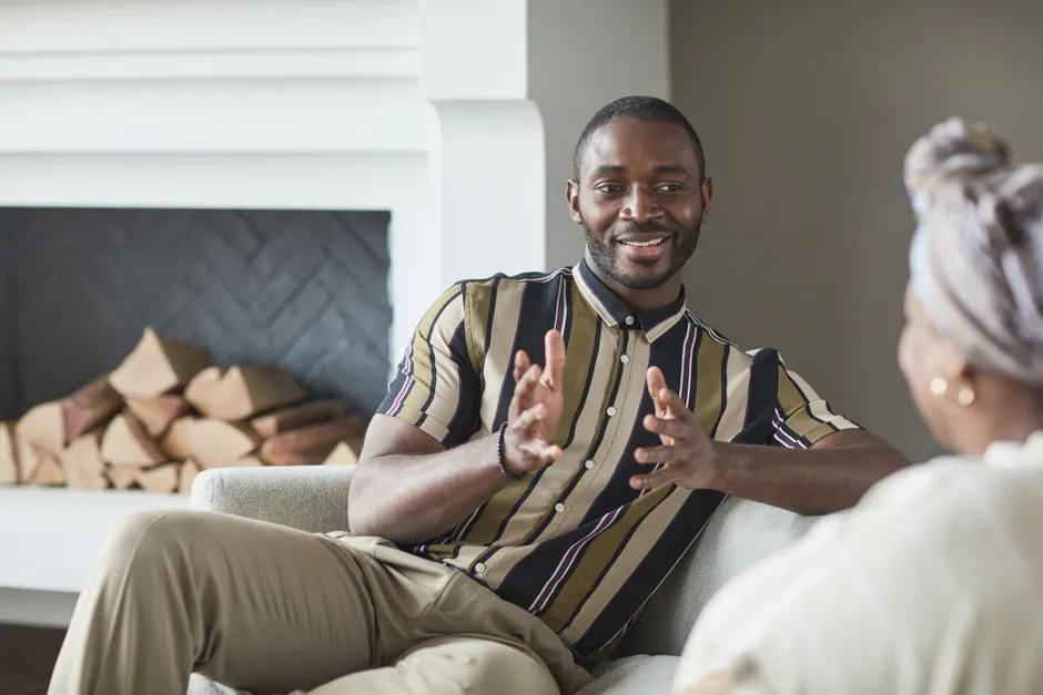Two adults enjoying a friendly conversation in a cozy modern living room setting.