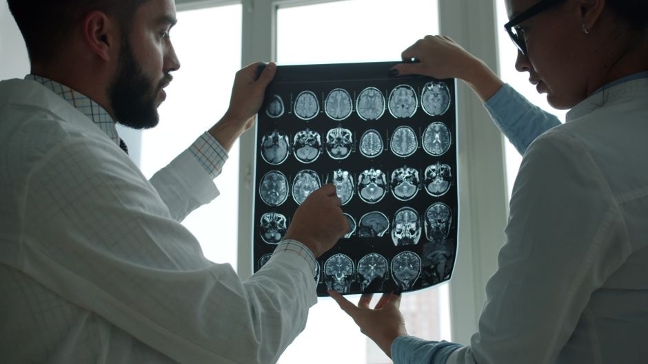 Two doctors examining MRI brain scans in a well-lit hospital room.
