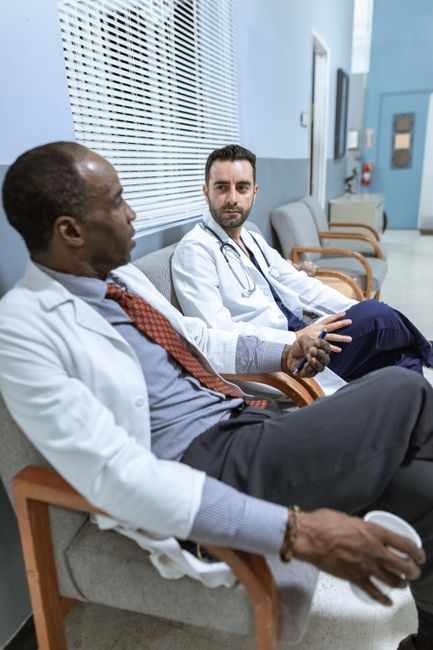 Two doctors sitting and discussing patient care in a hospital corridor.