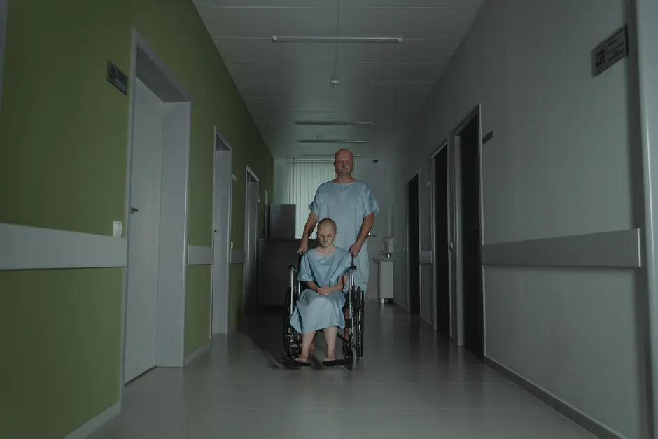 Two patients in hospital gowns navigate a hallway, symbolizing struggle and resilience.