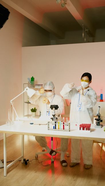 Two scientists in lab gear conducting experiments with test tubes and equipment.