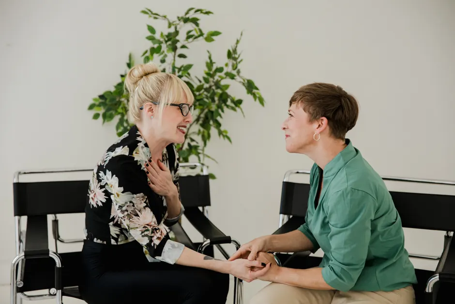 Risque suicidaire : repérer les facteurs sans enfermer la personne Two women sitting together, sharing a supportive and positive interaction indoors.
