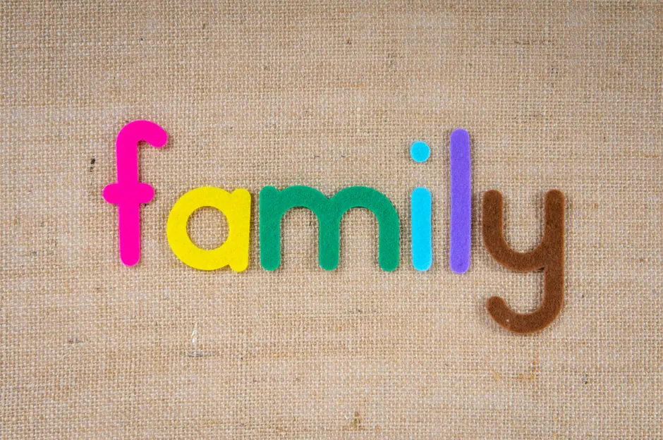 Vibrant letters spelling 'family' on a textured burlap background, emphasizing togetherness.