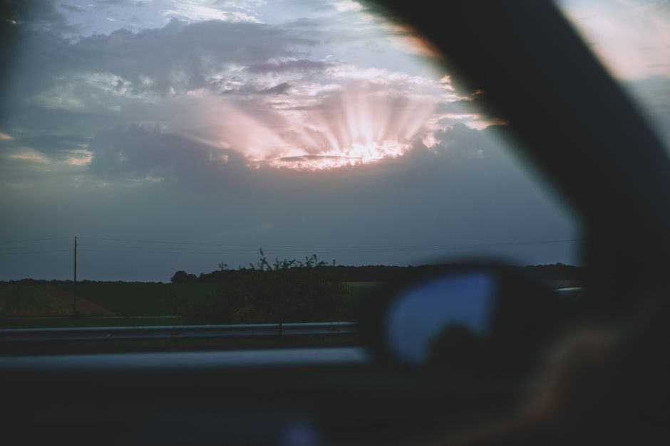 Rêver d’une tornade : le lien possible avec le stress et la perte de contrôle View of sunset cloudy sky with sunbeams through window of automobile riding along railing in countryside with green fields on evening