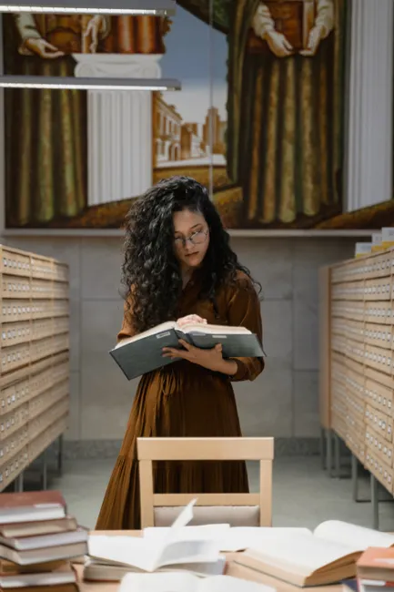 Woman reading a book in a vintage library surrounded by card catalog cabinets.