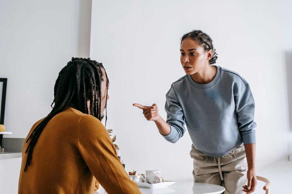 Famille d’origine : comment les schémas familiaux influencent le couple Young African American female standing near table while male sitting at kitchen and having argument