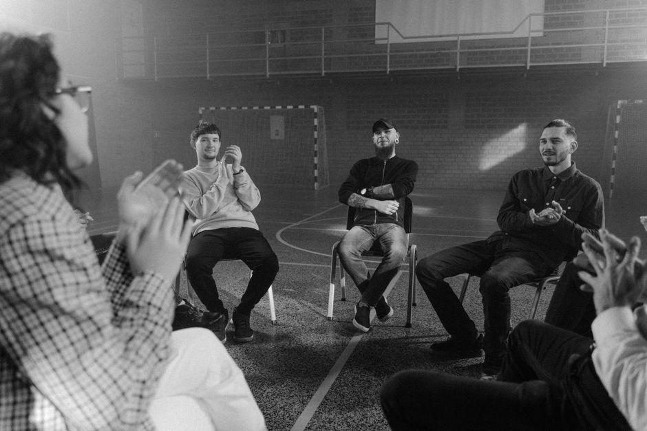 Programmes en 12 étapes : ce que la recherche montre sur l’alcool A black and white image of a support group engaged in a therapy session.