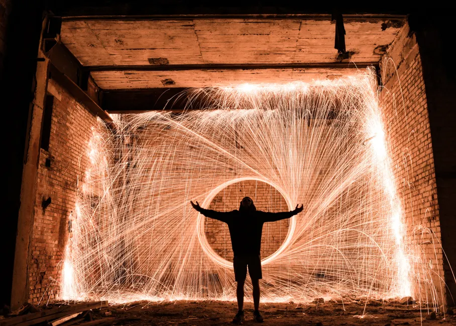A captivating long exposure shot with a silhouetted person and spark trails from steel wool photography.