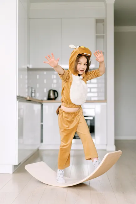A child in an animal costume balancing on a board indoors. Fun and playful activity at home.