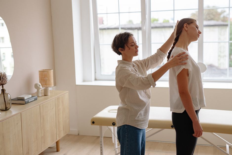 A chiropractor adjusts a patient's posture in a well-lit clinic room.