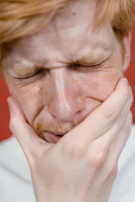 A close-up shot of a man with his eyes closed and hand on his face, showing deep emotion.