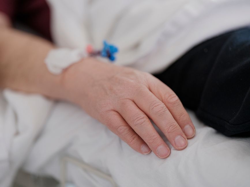 DMT thérapeutique en 2026 : ce que les études montrent et ce qu’elles ne prouvent pas A close-up view of a patient's hand resting on a bed with an intravenous drip connected.