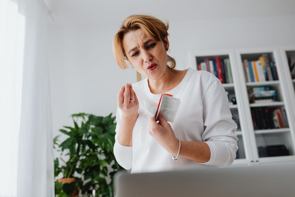Anxiété relationnelle : quand le doute prend toute la place A concerned woman reviews her finances while holding receipts, showing a worried expression.